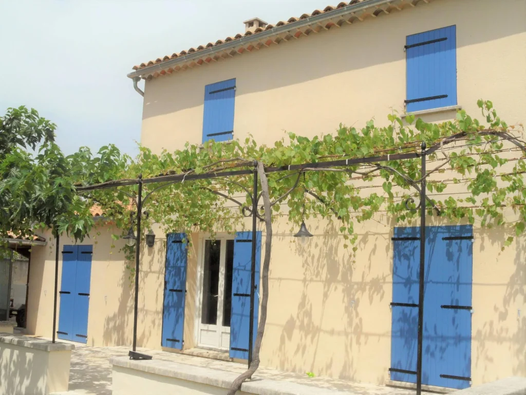 maison traditionnelle au fenêtres et porte fenêtres avec de volets battants bleus