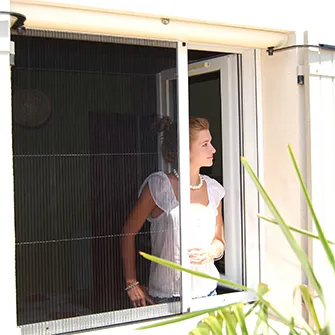 Jeune femme à la fenêtre équipée d'une moustiquaire